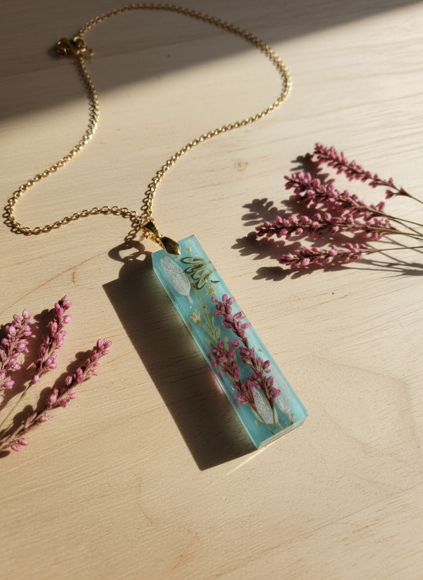 "Handmade turquoise resin pendant with pink heather flowers displayed on wooden background"