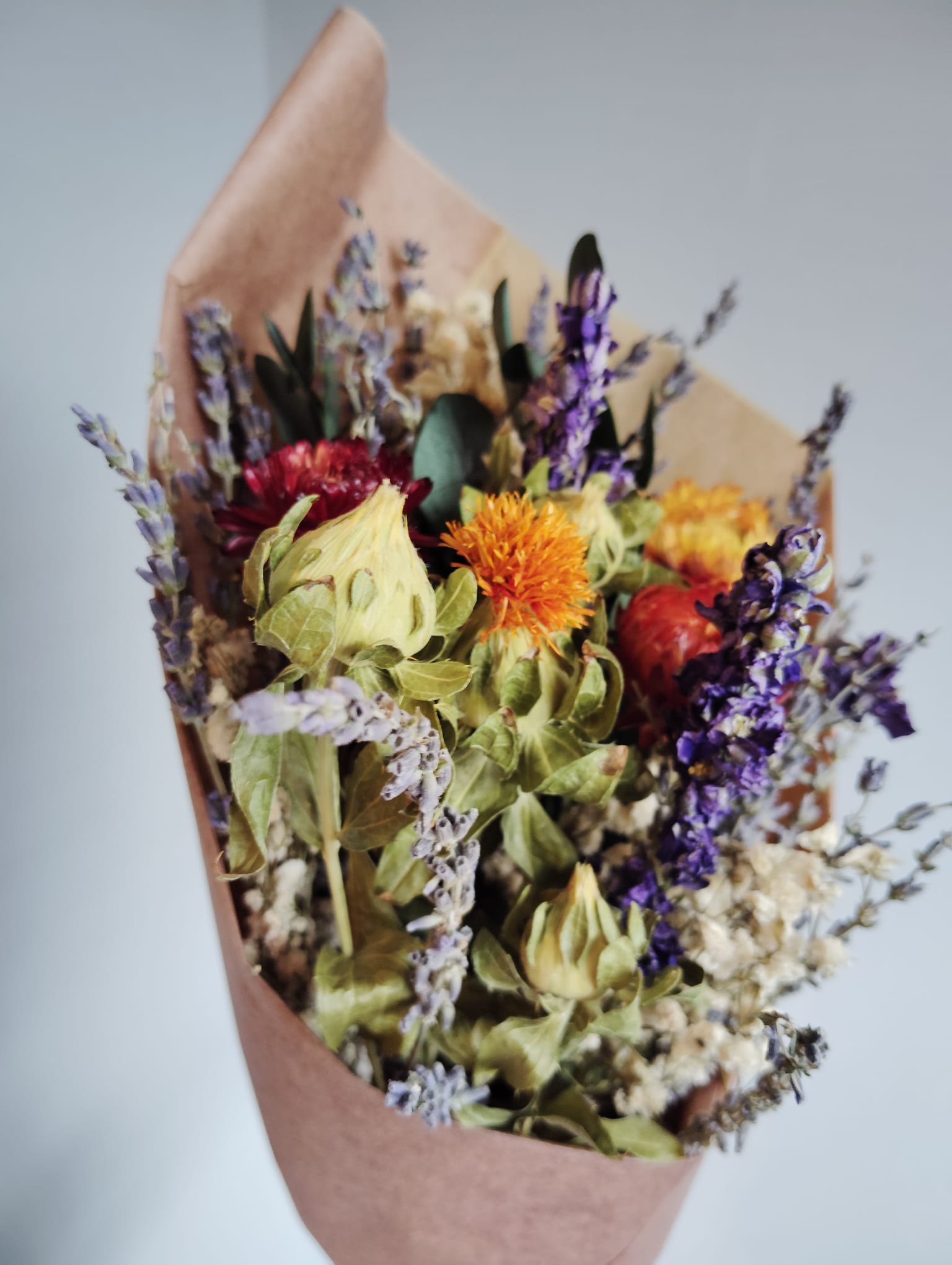 Everlasting floral arrangement with warm autumn colors, including red strawflowers and purple larkspur, handmade in Dublin.