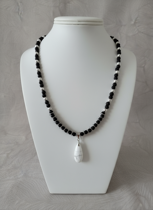 "Volcanic stone necklace with white howlite pendant and silver hematite beads on grey background"