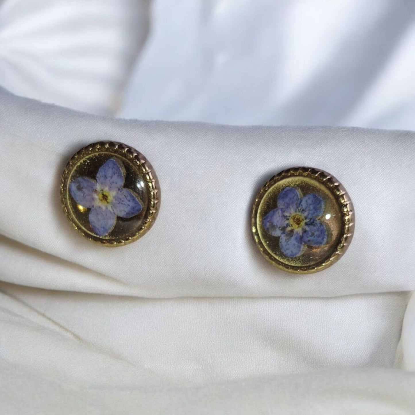 Forget me not flower stud earrings with blue pressed flowers in gold frame on white background