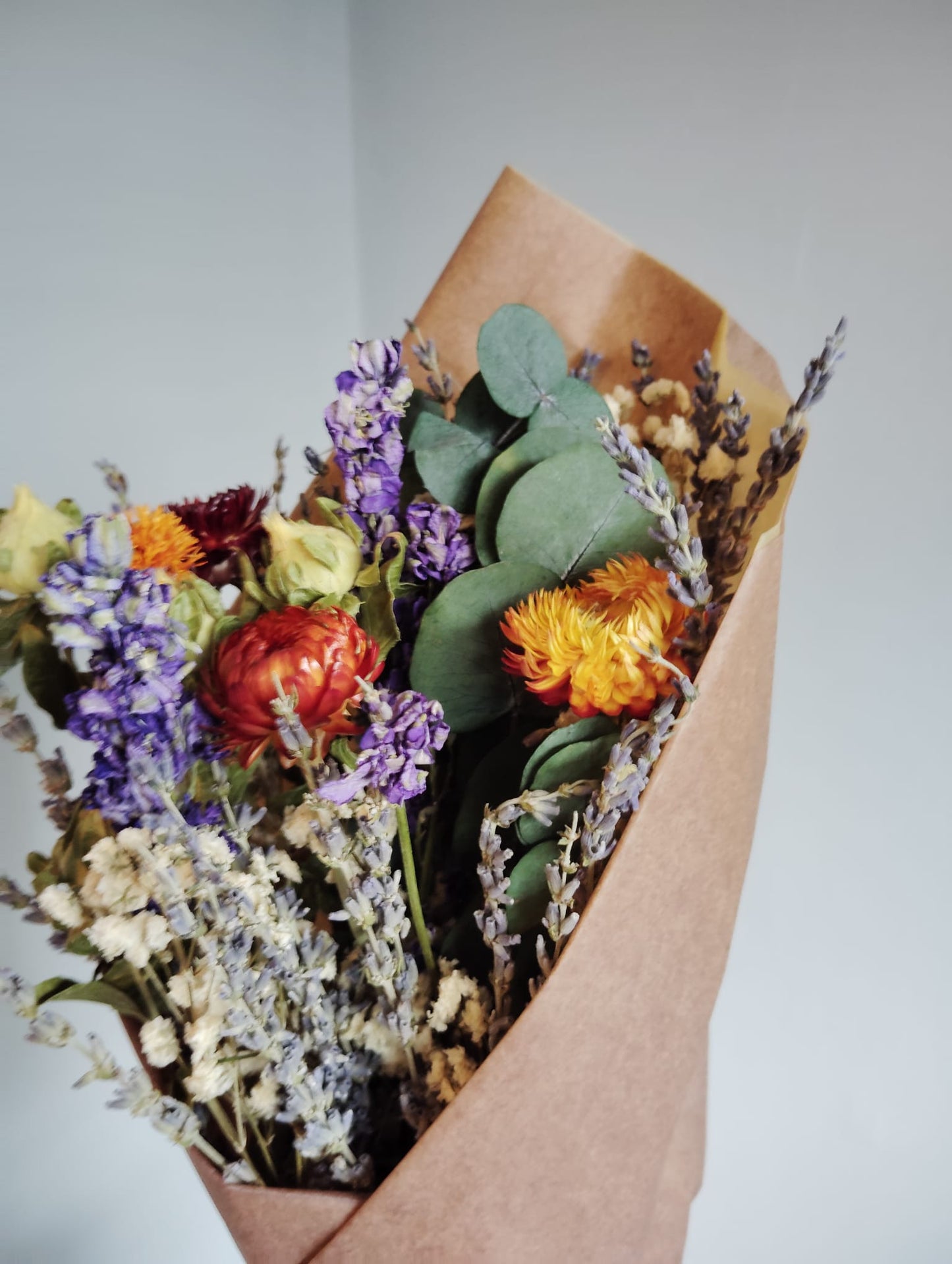 Hand-tied dried flower bouquet with fragrant purple lavender, orange safflowers, and preserved eucalyptus