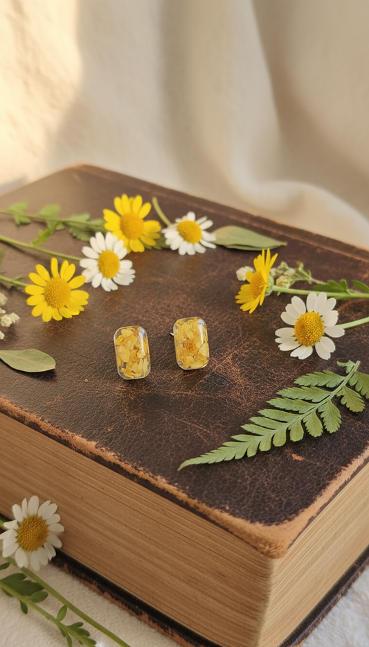 Rectangular yellow daisy petal resin earrings on vintage book with botanical decoration
