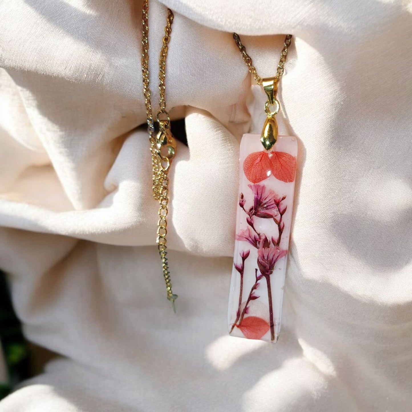 Pink botanical resin necklace with delicate pressed flowers. Gold stainless steel chain. Unique handmade jewelry crafted in Dublin, Ireland. Perfect gift for her.