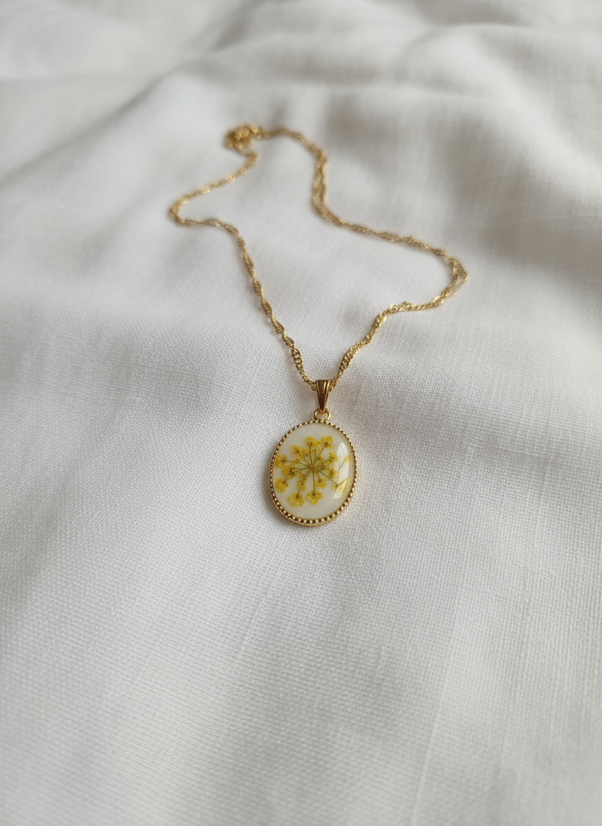 Yellow pressed flower oval pendant necklace with gold twisted chain on white background
