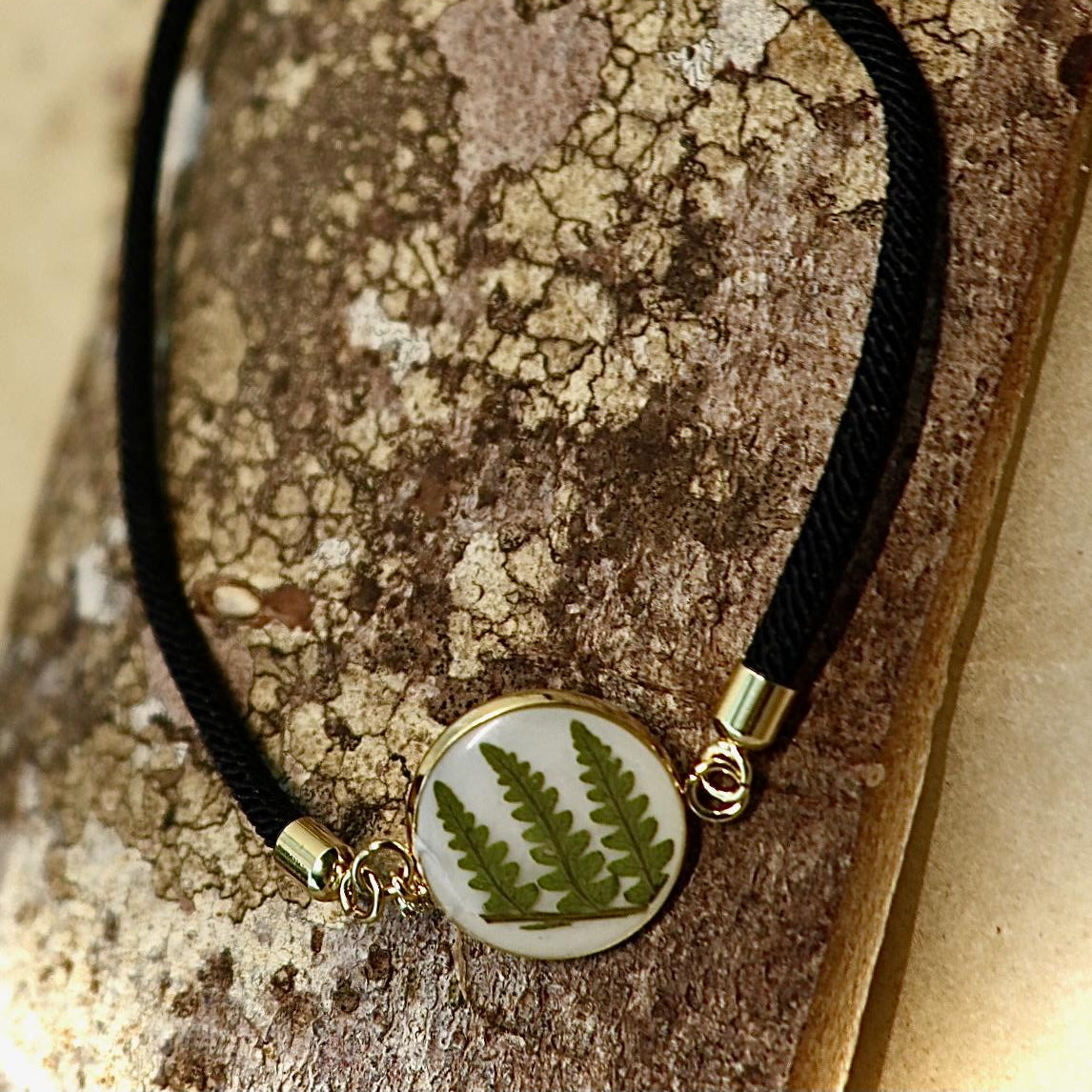 Close-up of delicate real Irish fern detail encased in clear resin on a handmade botanical bracelet