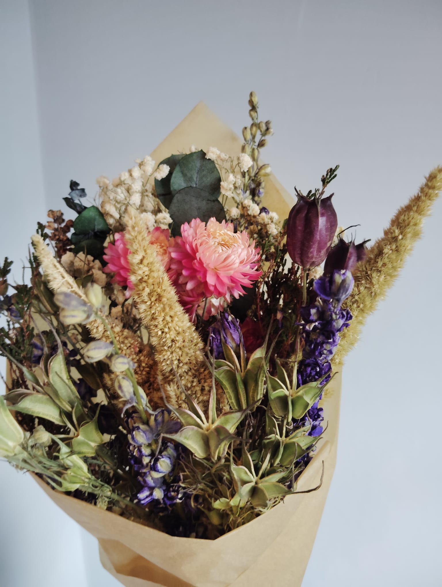 Rustic bohemian style dried floral arrangement with vibrant pink everlastings and preserved foliage for home decor