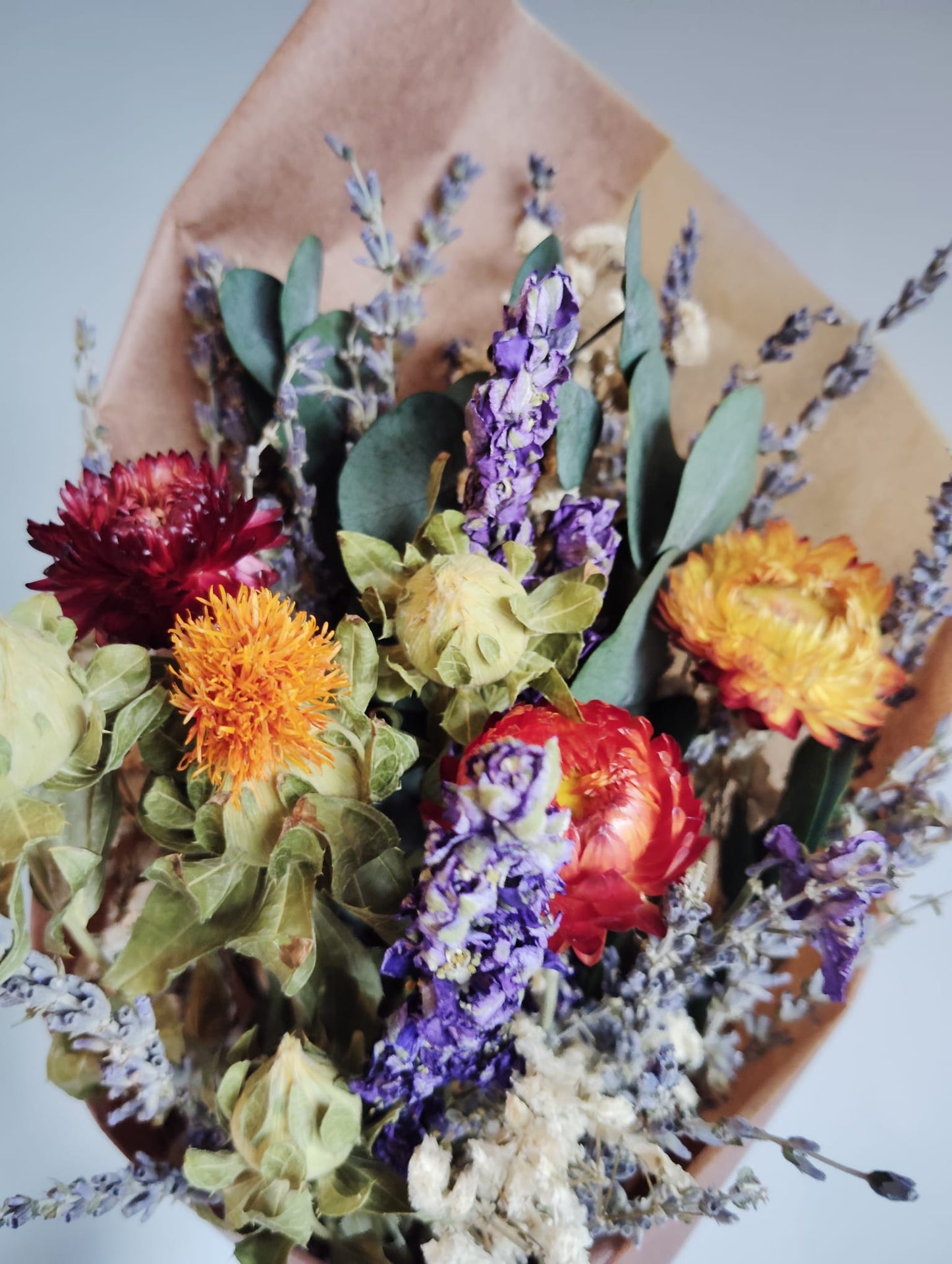 Rustic botanical gift featuring a large lavender and orange flower bunch wrapped in sustainable kraft paper.